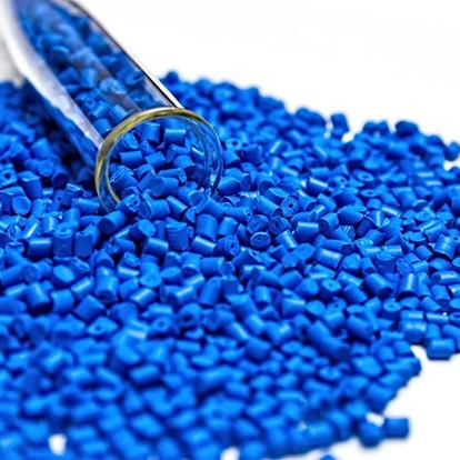 Blaues Granulat verteilt sich auf einer weißen Oberfläche. Ein teils mit Granulat gefülltes Glasrohr liegt auf der Seite.