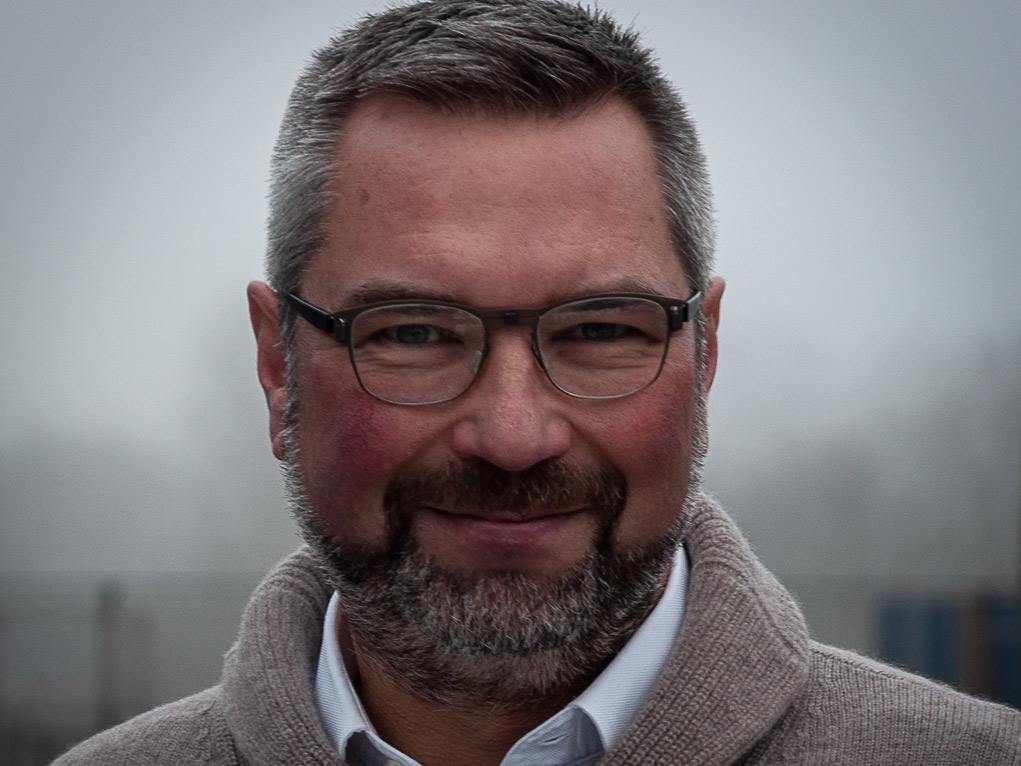 Dr. Achim Gandorfer blickt lächelnd, frontal in die Kamera. Er trägt eine Brille und einen hellbraunen Pullover