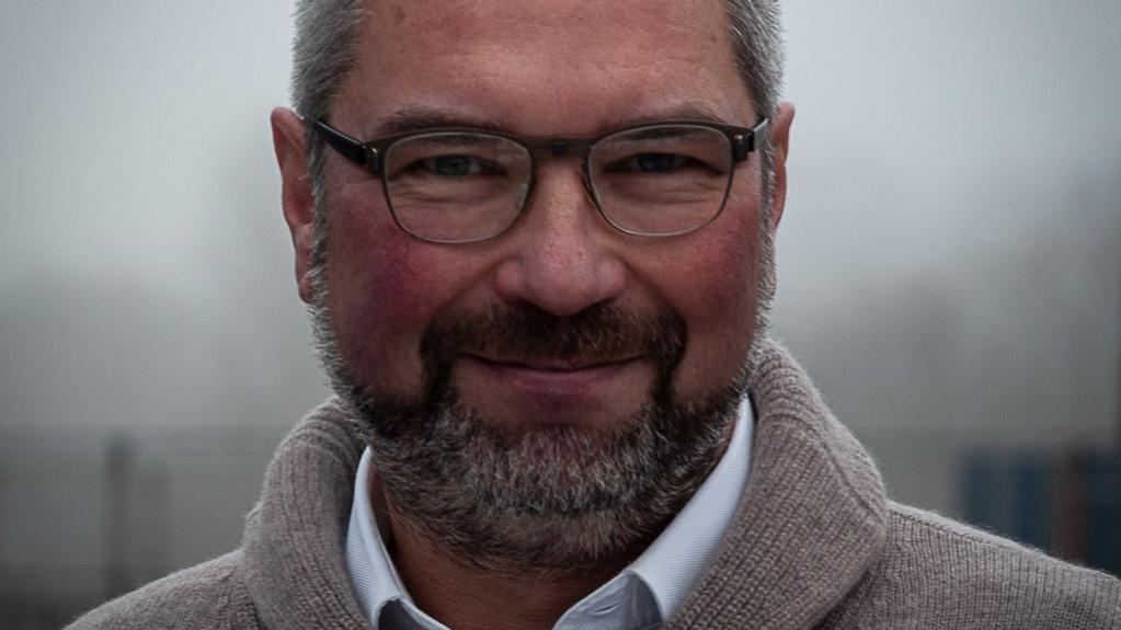 Dr. Achim Gandorfer blickt lächelnd, frontal in die Kamera. Er trägt eine Brille und einen hellbraunen Pullover