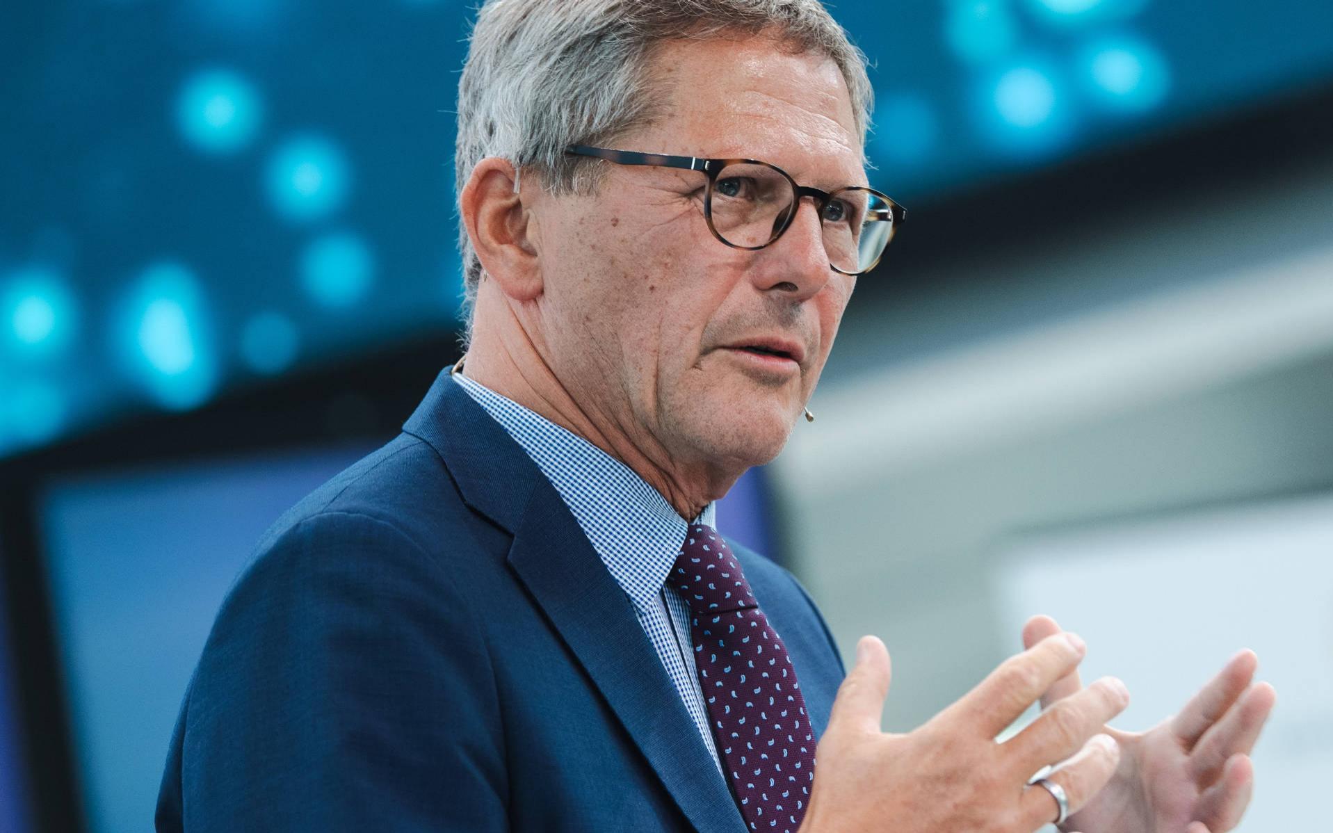 Porträt von Prof. Dr. Michael Kaschke. Er trägt einen blauen Anzug hebt gestikulierend die Hände.