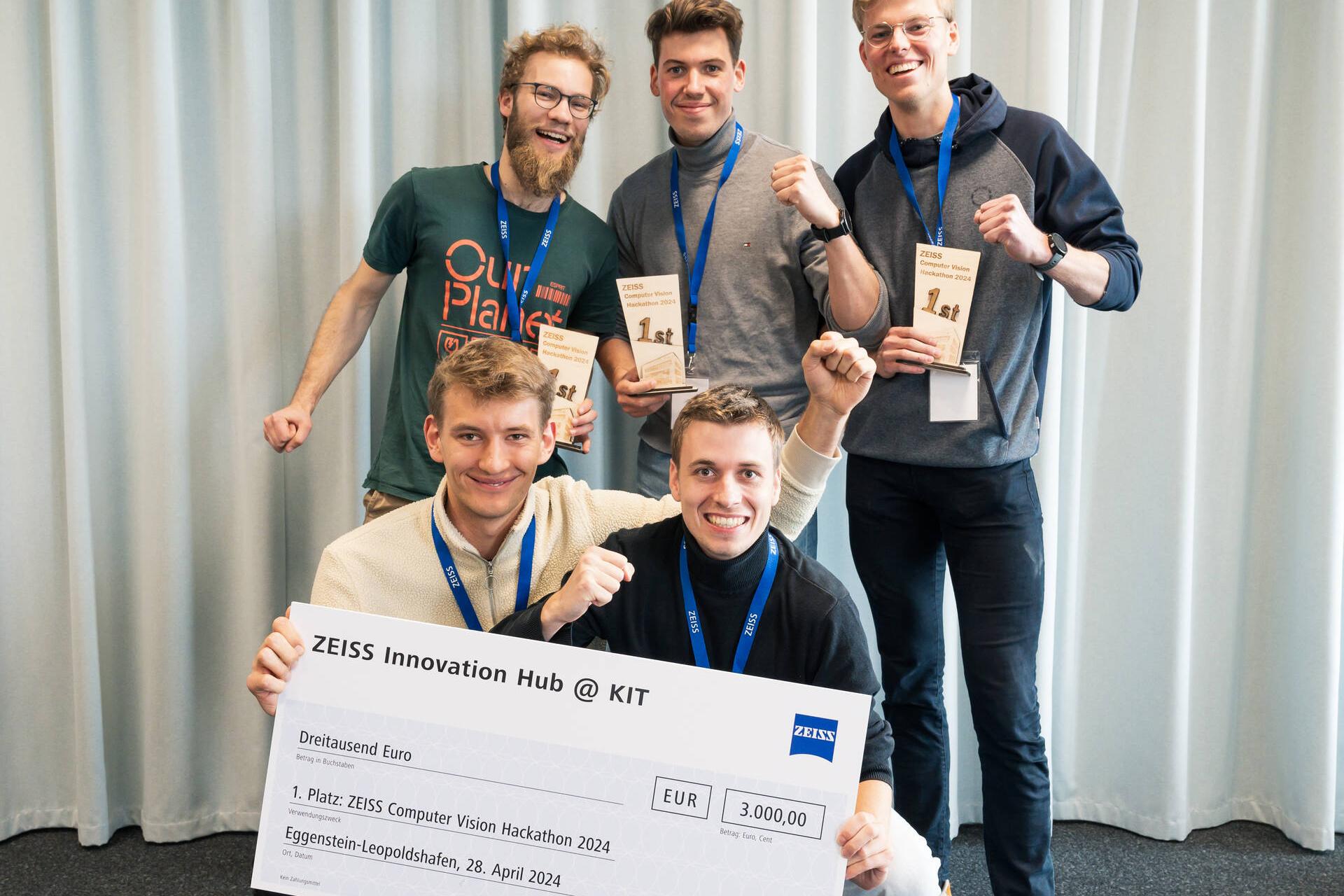 Ein Gruppenfoto vom Gewinnerteam des ZEISS Computer Vision Hackathon 2024. Zwei der fünf Teilnehmer halten einen überdimensionalen Scheck.