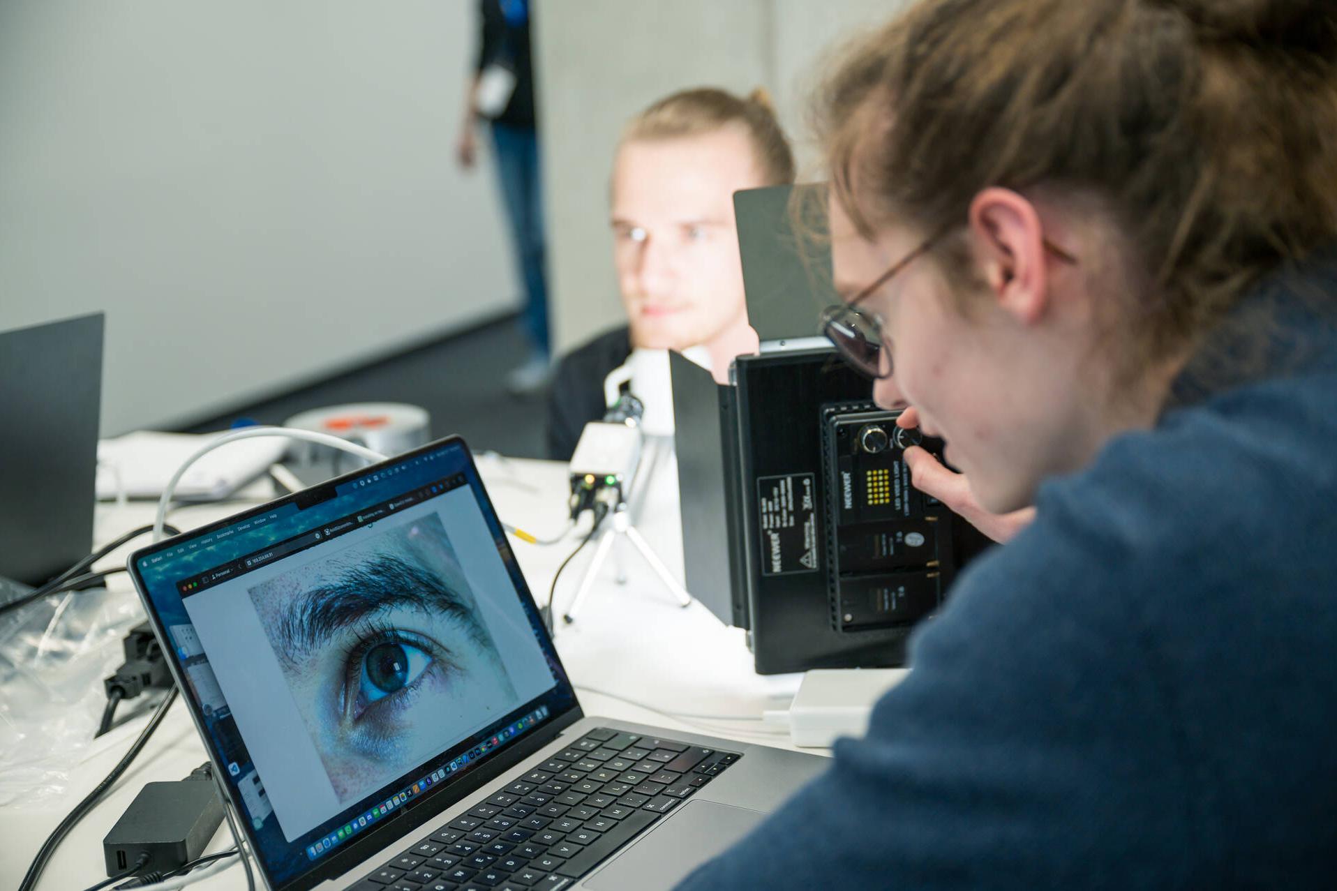 Ein Hackathon Teilnehmer schaut sich ein Foto eines menschlichen Auges auf einem Laptop an.