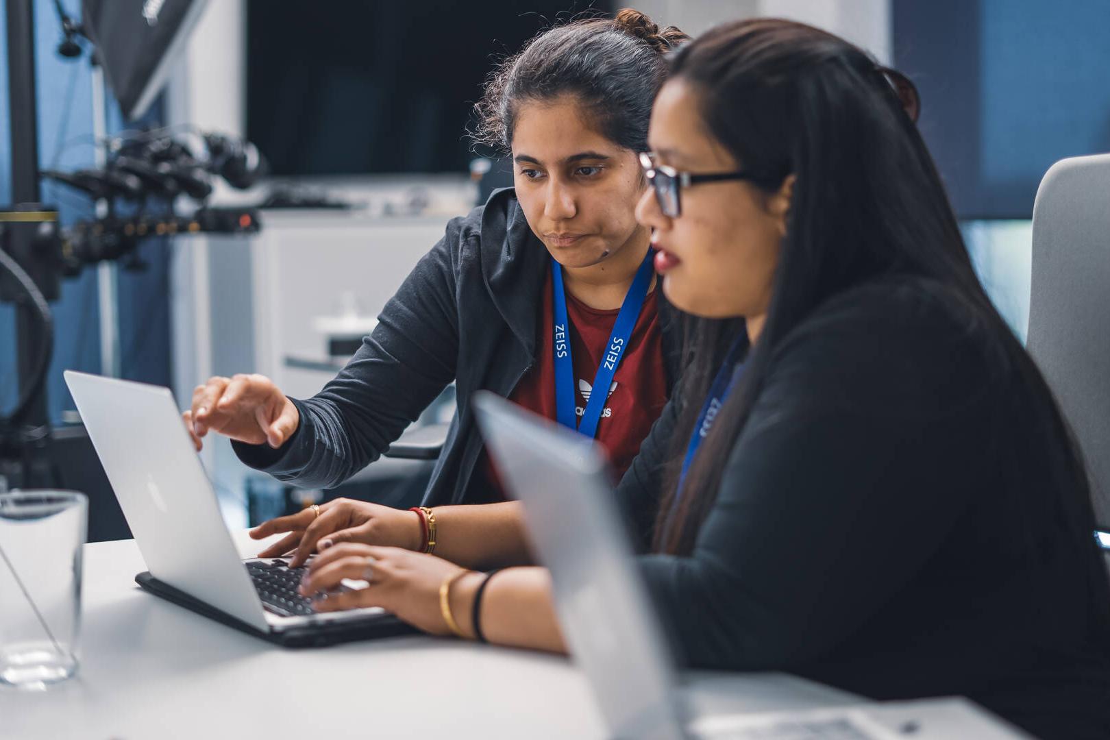 Zwei Hackathon Teilnehmer sitzen an einem Schreibtisch und arbeiten gemeinsam an ihrem Projekt.