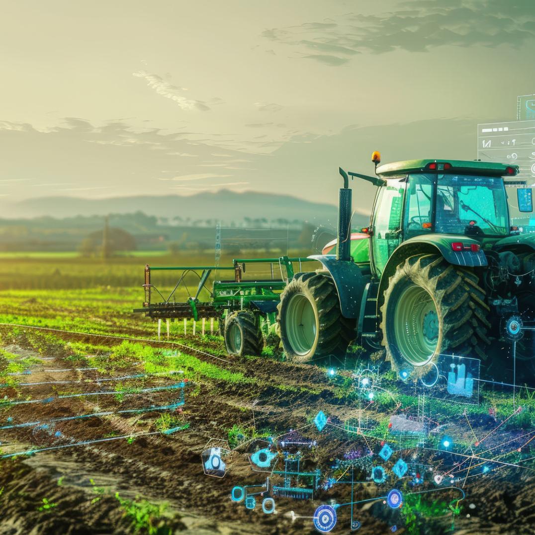 Ein Traktor fährt über ein Feld, dem Sonnenuntergang entgegen.