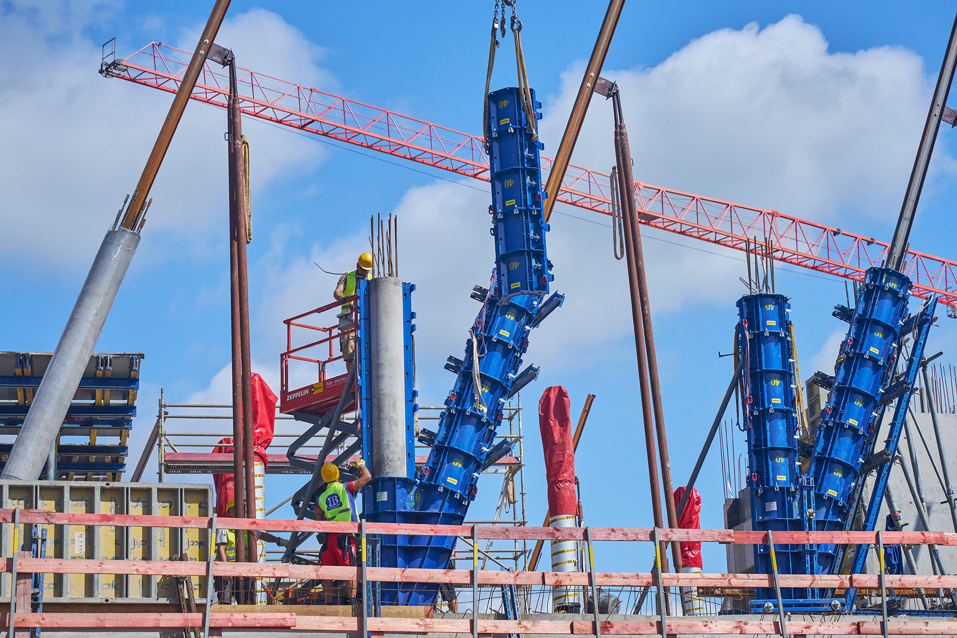 Die blauen Stahlschalungen umhüllen die Traggerüstkonstruktion wie eine Gießform, um sie anschließend mit Beton zu füllen und somit neue Betonstützen zu errichten. 