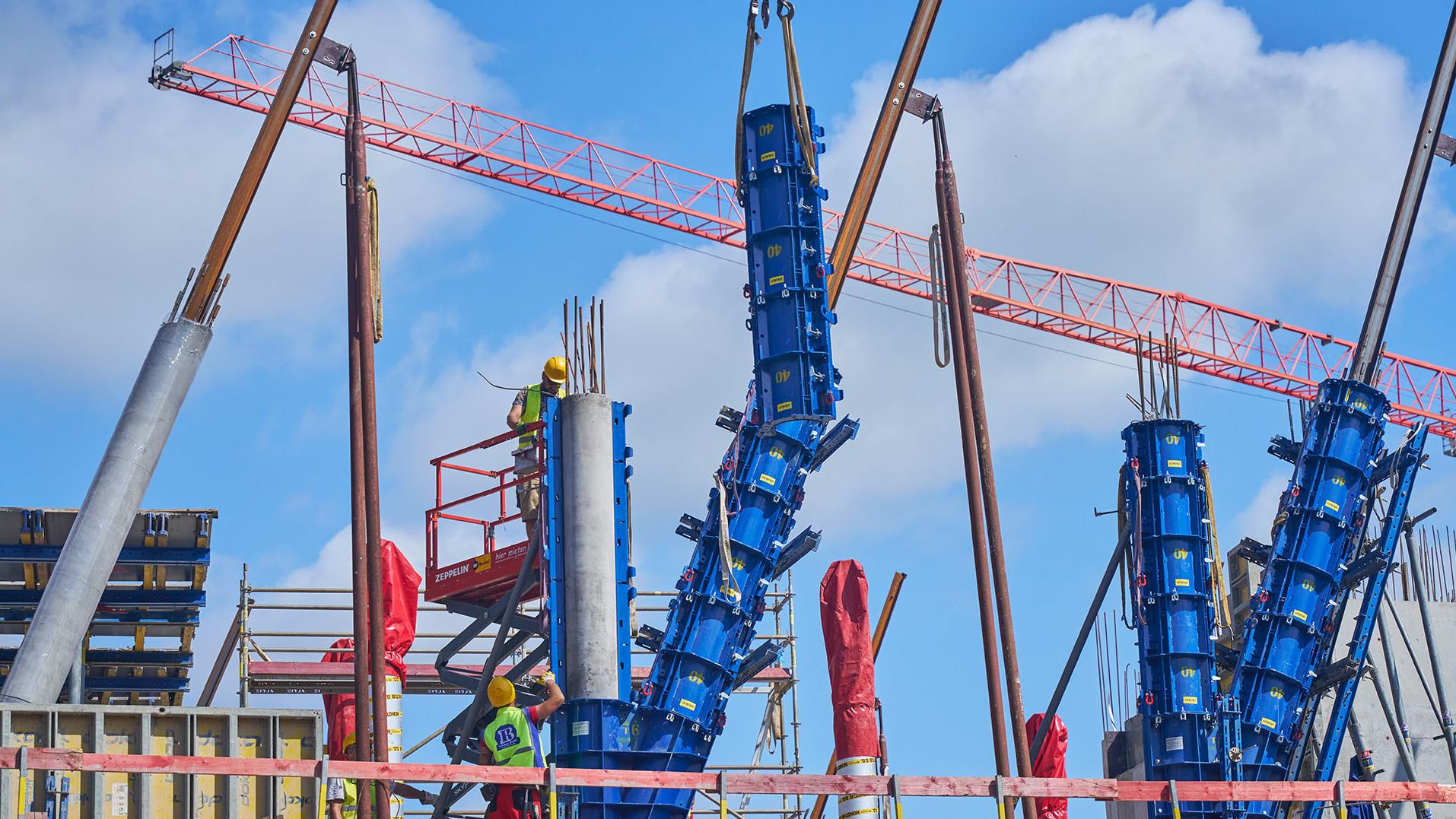 Die blauen Stahlschalungen umhüllen die Traggerüstkonstruktion wie eine Gießform, um sie anschließend mit Beton zu füllen und somit neue Betonstützen zu errichten. 