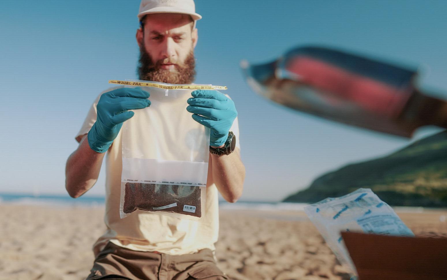 Wissenschaftler begutachtet eine Probe am Strand
