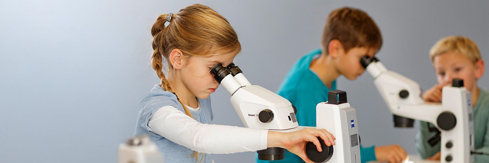 Kinder, die an einem Mikroskop arbeiten 