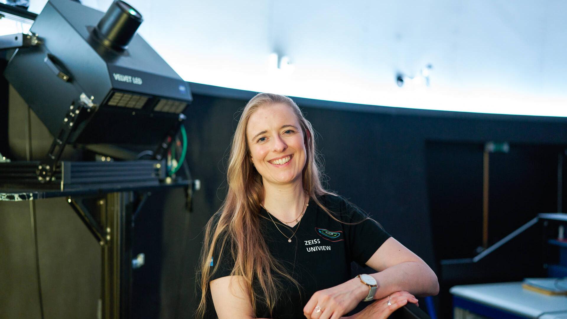 Sophia Dannberg steht im Planetarium vor einem Projektor