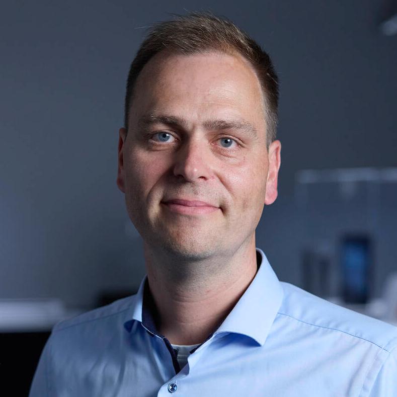 Dr. Dennis Lehr, Teil des Leitungsteams der ZEISS Microoptics, steht in einem Ausstellungsraum und blickt in die Kamera.