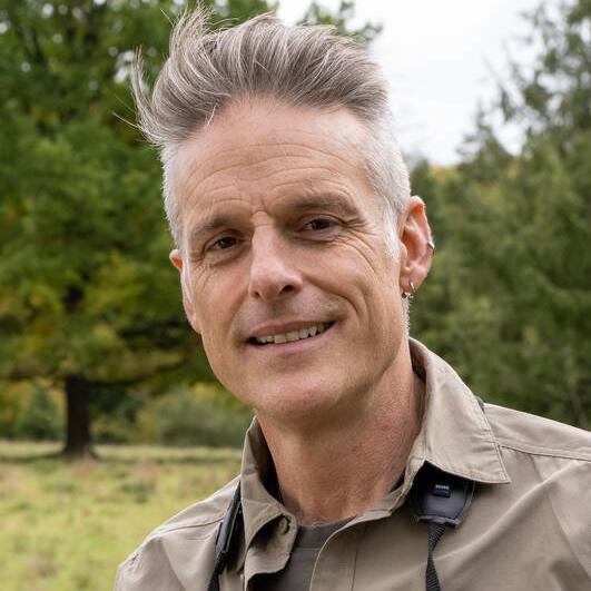 Porträtbild von Nick Baker. Es schaut direkt in die Kamera und lächelt freundlich.