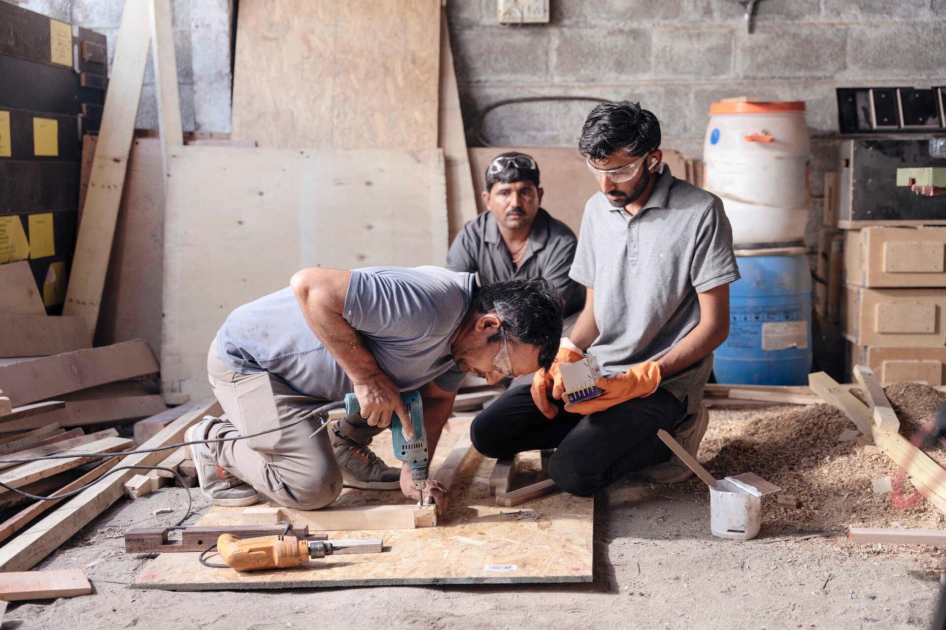 Sharma, Radia und ein Kollege bauen neue Bänke aus weggeworfenen Holzkisten