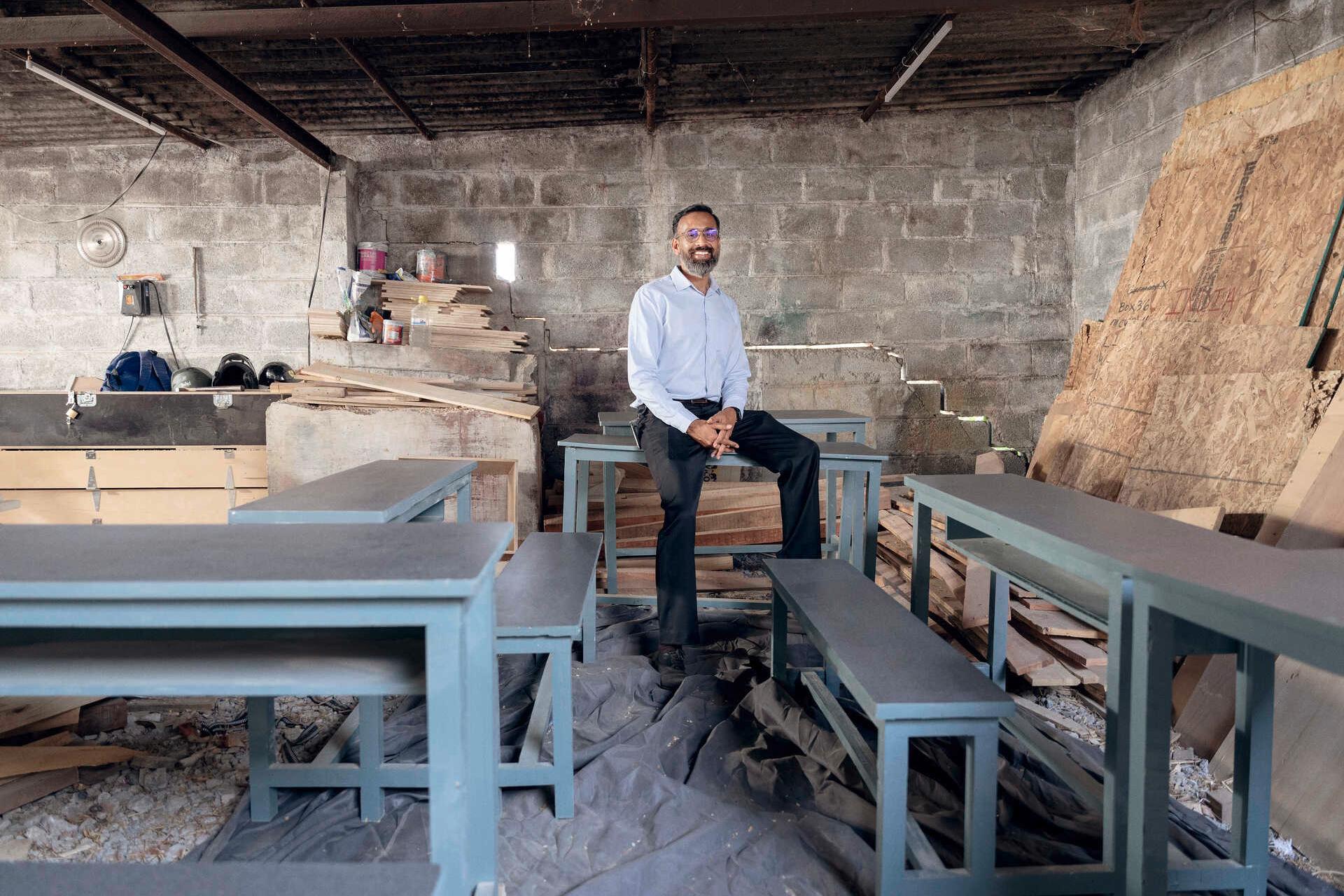 Manoj Sharma sitzt auf einer Bank in der Holzwerkstatt