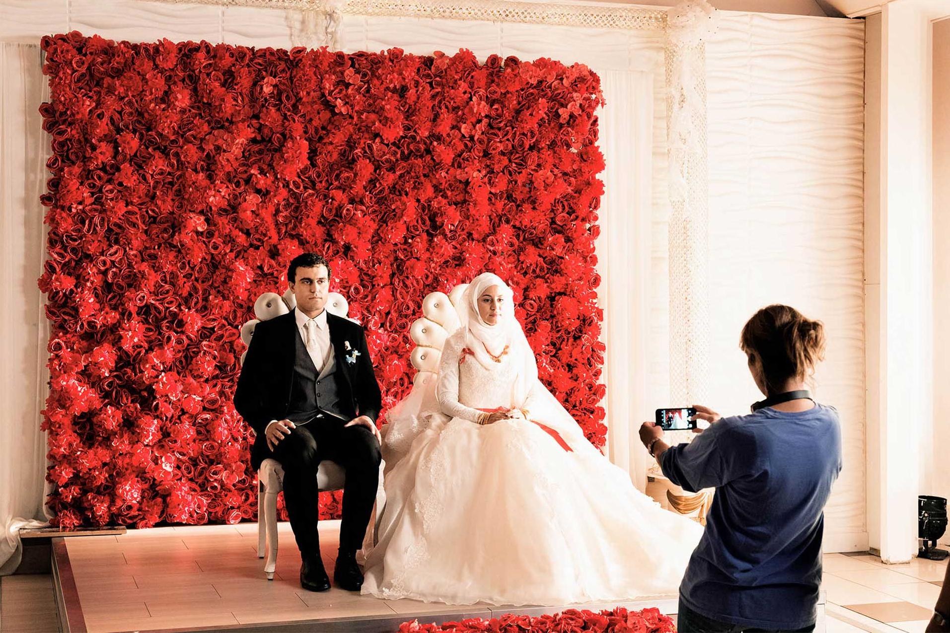 Sherry Hormann macht eine Aufnahme von einem Brautpaar vor einer Wand aus Blumen