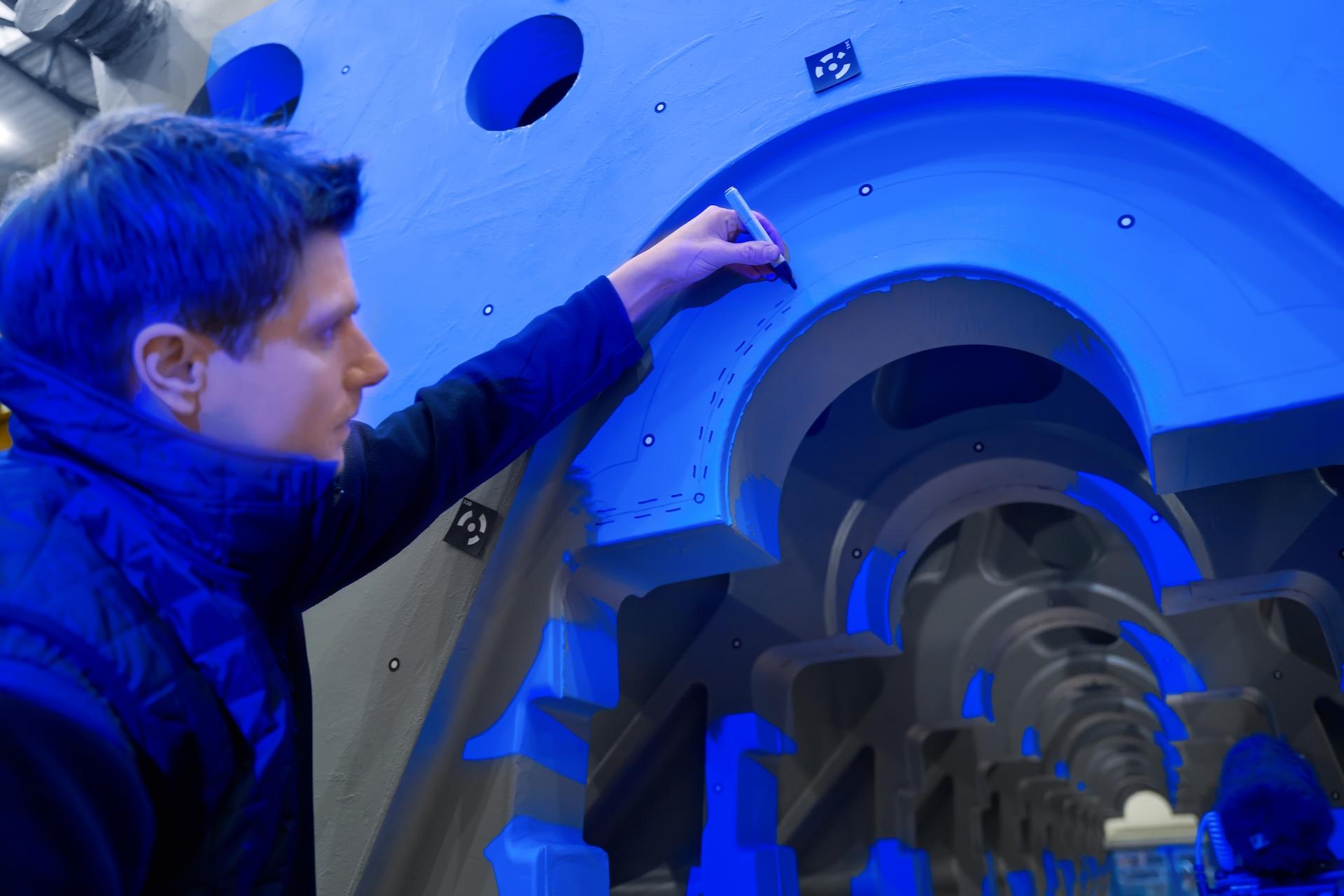 Engineer Dr. Georg Geier inspecting blue industrial structure.