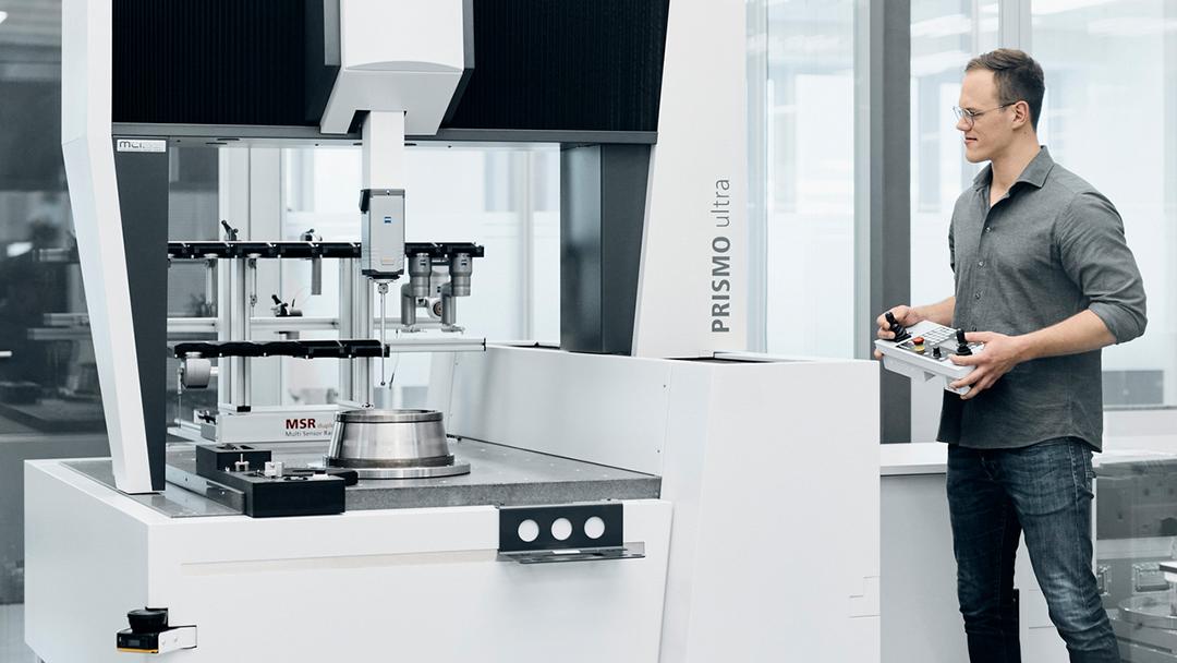 Ein Messtechniker misst ein Bauteil mit dem nach DIN EN ISO 10360 kalibrierten KMG von ZEISS.