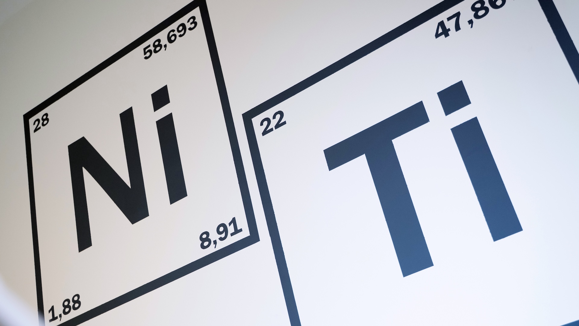 Wandgrafik mit den chemischen Elementen Nickel (Ni) und Titan (Ti), dargestellt als Kacheln des Periodensystems.