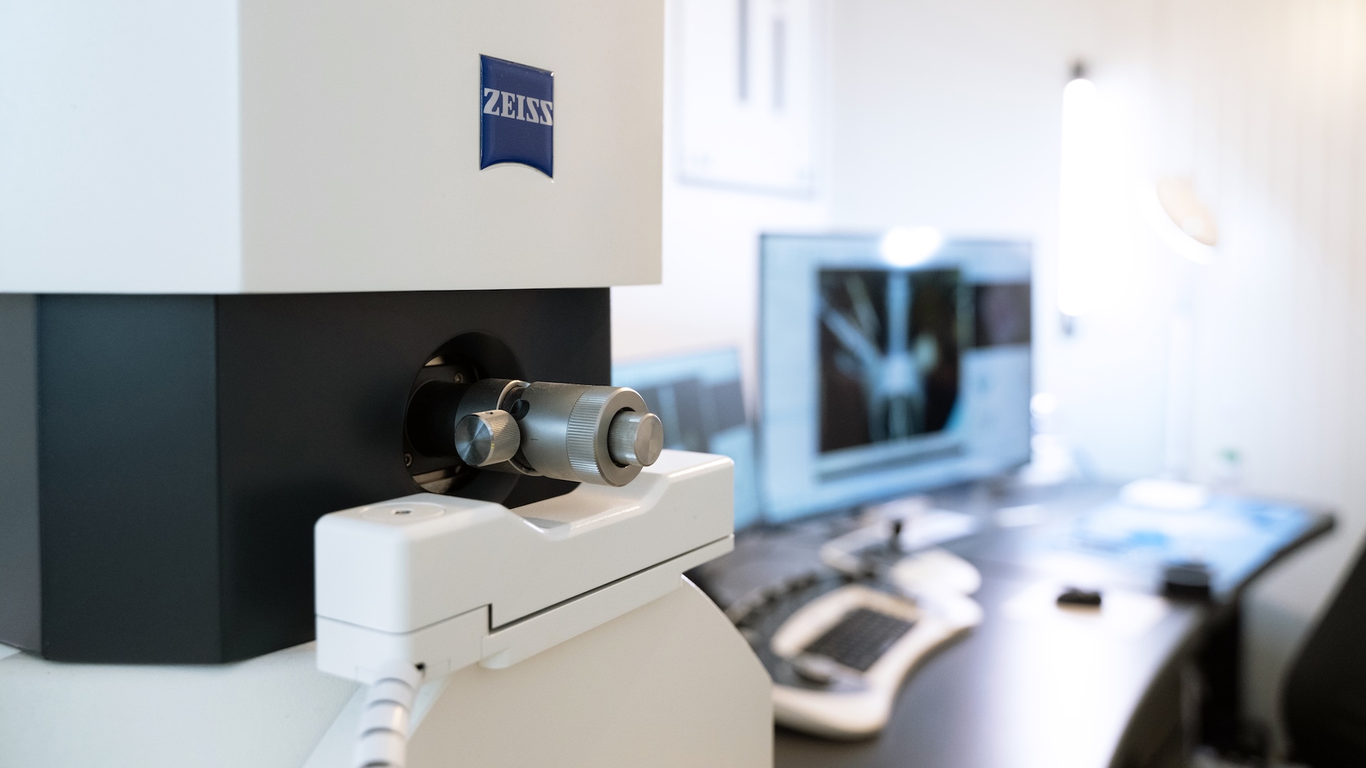 Nahaufnahme eines ZEISS EVO vor einer Workstation mit einem Computer, der ein gescanntes Bild anzeigt.
