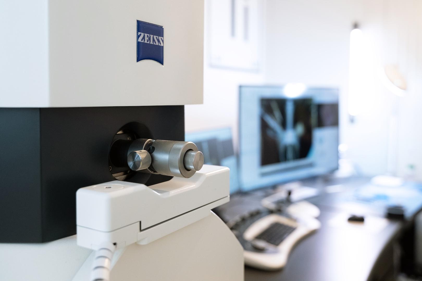 Nahaufnahme eines ZEISS EVO vor einer Workstation mit einem Computer, der ein gescanntes Bild anzeigt.