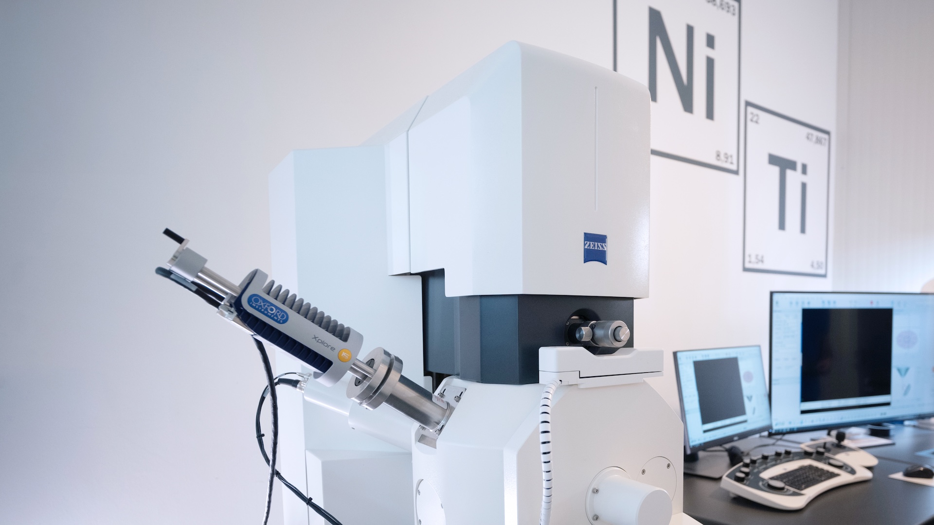 Aufbau eines ZEISS Elektronenmikroskops in einer Laborumgebung mit umliegenden Computerarbeitsplätzen und Elementtafeln.