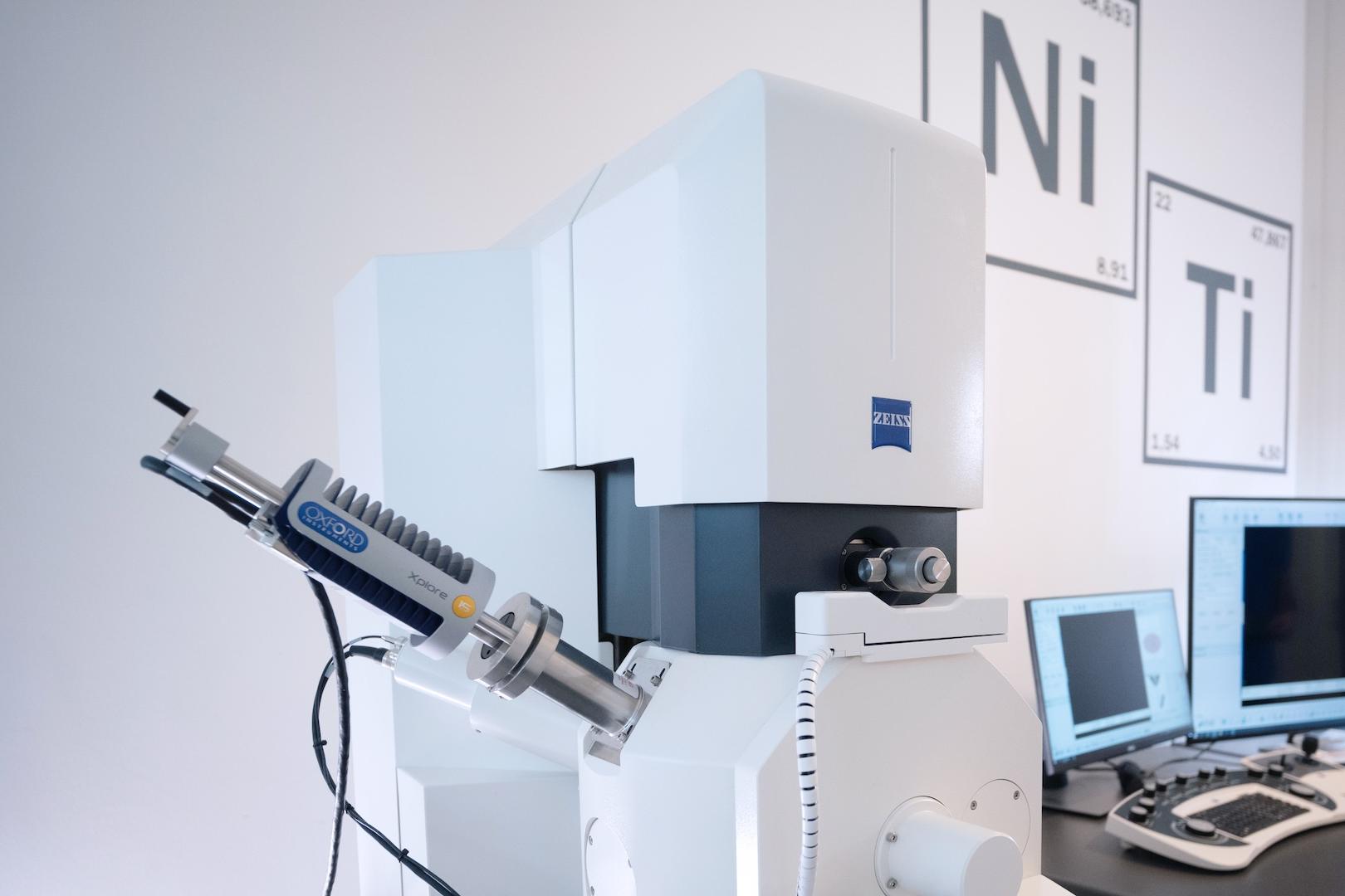 Aufbau eines ZEISS Elektronenmikroskops in einer Laborumgebung mit umliegenden Computerarbeitsplätzen und Elementtafeln.