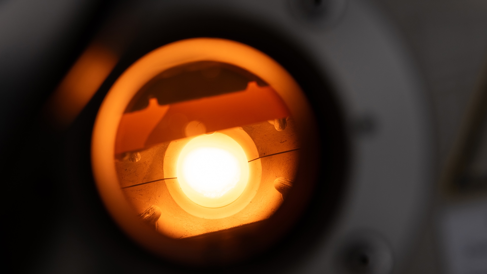 Nahaufnahme einer beleuchteten optischen Komponente in einem wissenschaftlichen Instrument, repräsentativ für die Feinwerktechnik von ZEISS.