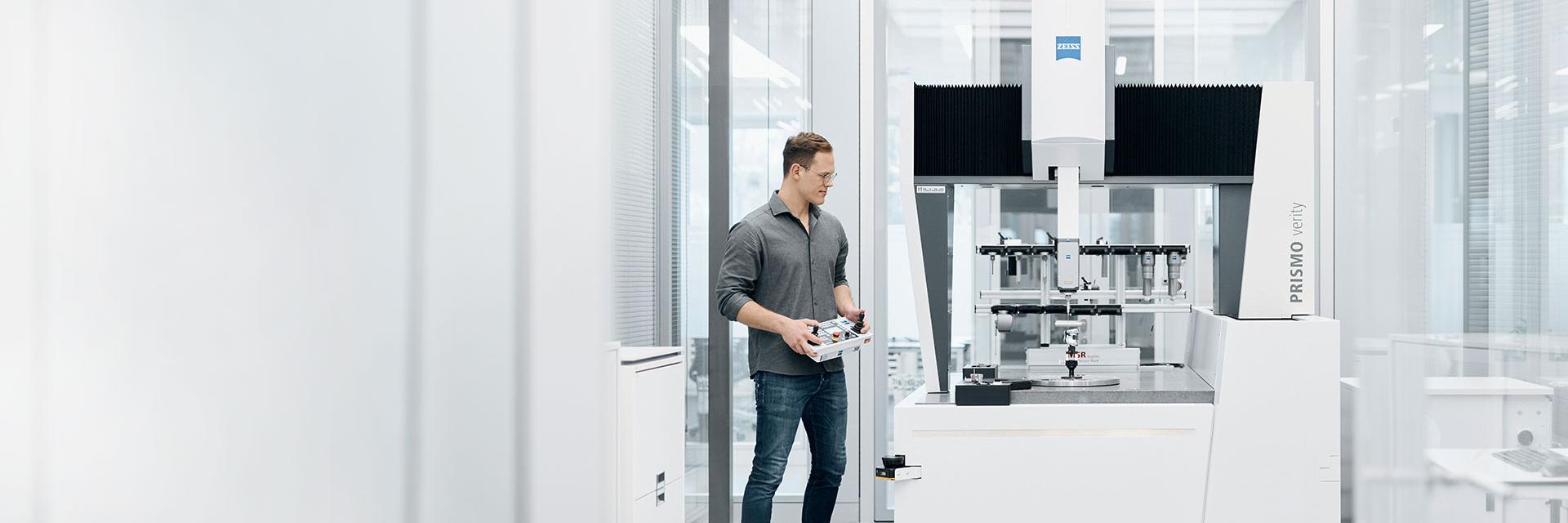 Ein Messtechniker misst ein Bauteil mit dem nach DIN EN ISO 10360 kalibrierten KMG von ZEISS.