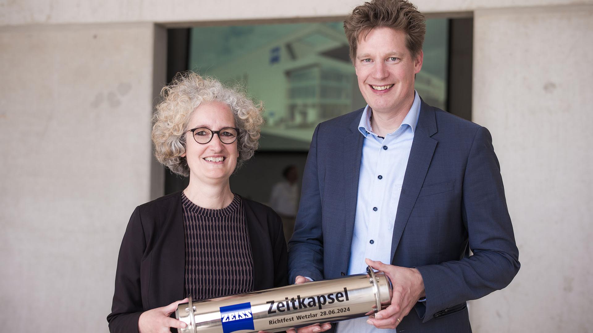 Standortleiterin Katrin Ariki und Chief Operating Officer Christoph Hensche beim Richtfest der neuen ZEISS Multifunktionsfabrik in Wetzlar mit der Zeitkapsel.