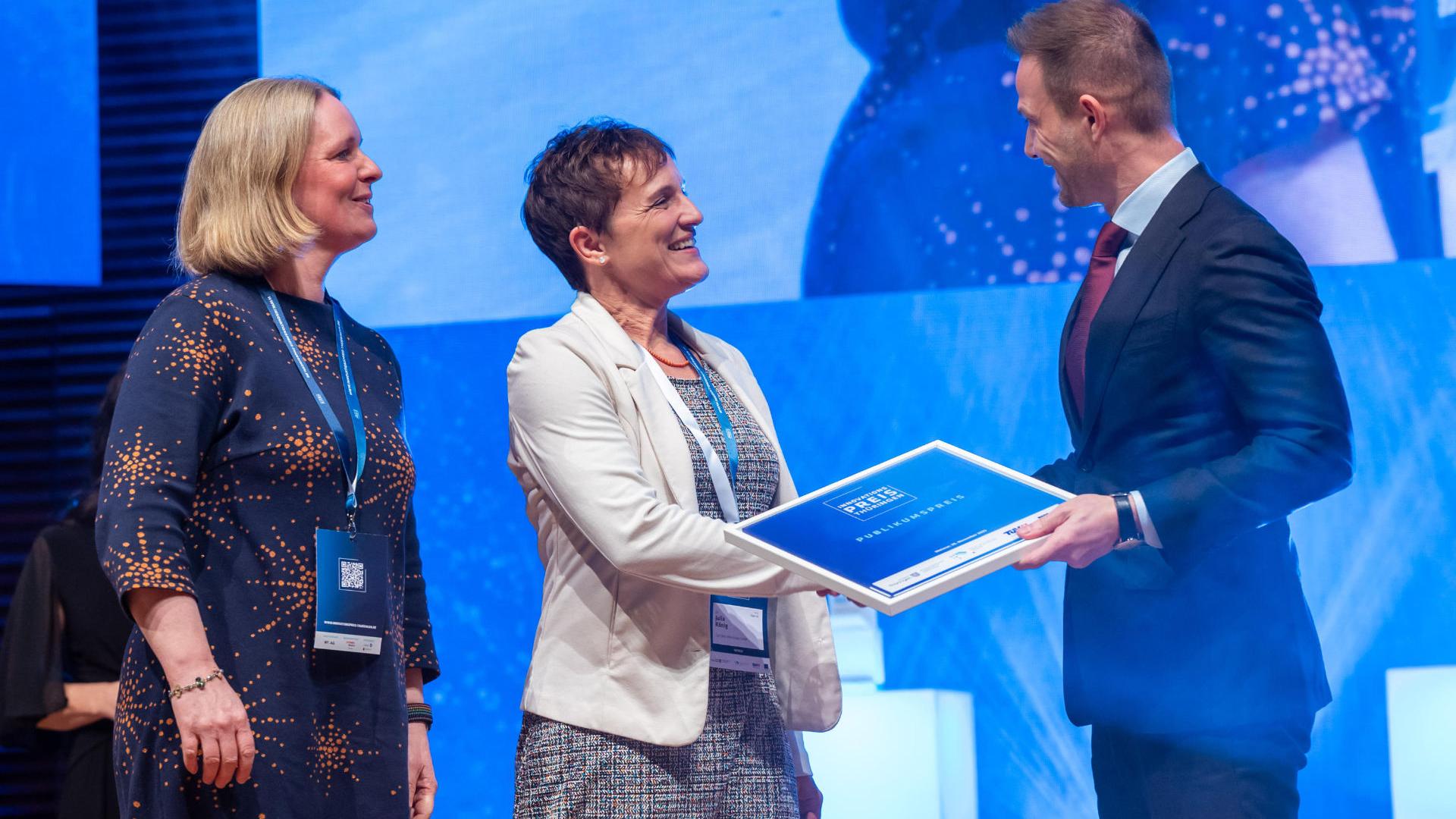 Annette Bergter (Businessmanager) und Julia König (Produktmanager) von der Carl Zeiss Microscopy GmbH nehmen den Publikumspreis von Stefan Gruhner (Chef der Staatskanzlei und Thüringer Minister für Bundes- und Europaangelegenheiten, Sport und Ehrenamt) entgegen.