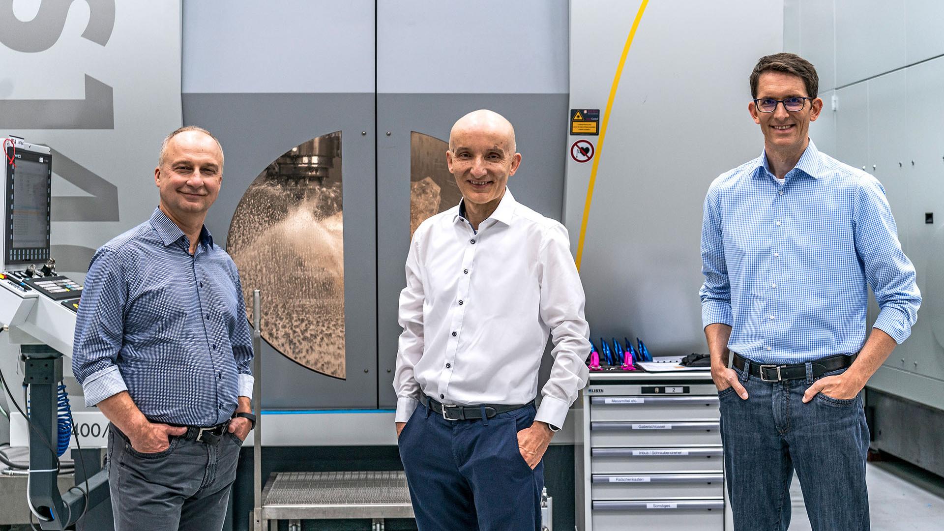 Dr. Sergiy Yulin, Dr. Peter Kürz und Dr. Michael Kösters stehen in der Produktionshalle der EUV-Technologie