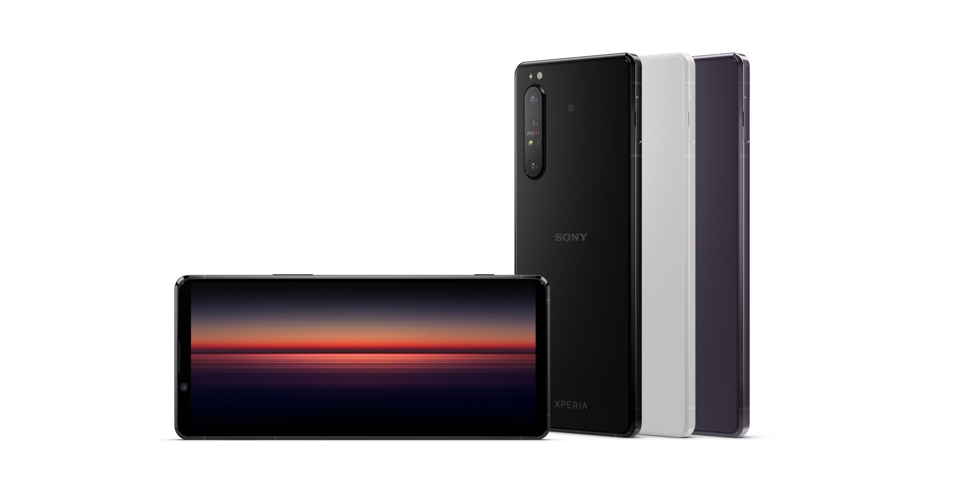 Drei Sony-Smartphones in unterschiedlichen Farben werden aufrecht stehend präsentiert, wobei eines der Telefone einen farbenfrohen Bildschirm mit Sonnenuntergangsmotiv und ZEISS-Optik zeigt.
