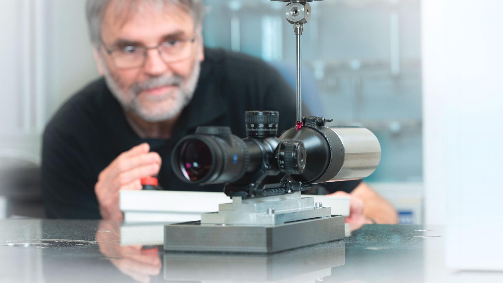 Engineer testing a ZEISS riflescope mounted on equipment to ensure stability and shot-proof performance.