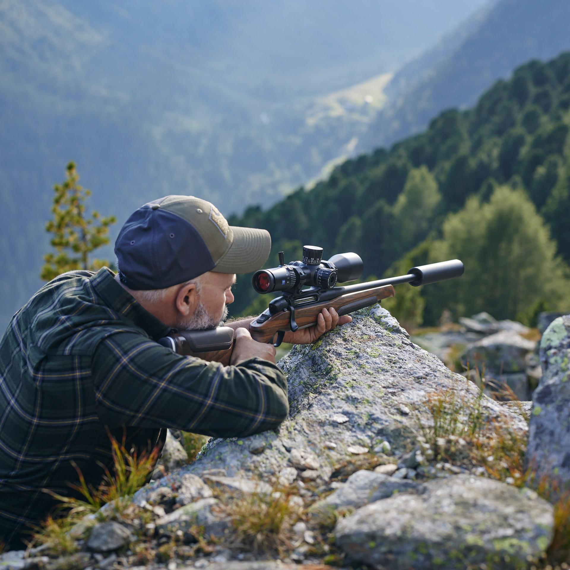 Hunter aiming with a rifle equipped with the ZEISS LRP S3 425-50 riflescope in rocky mountain terrain – ideal for medium to long-range targeting