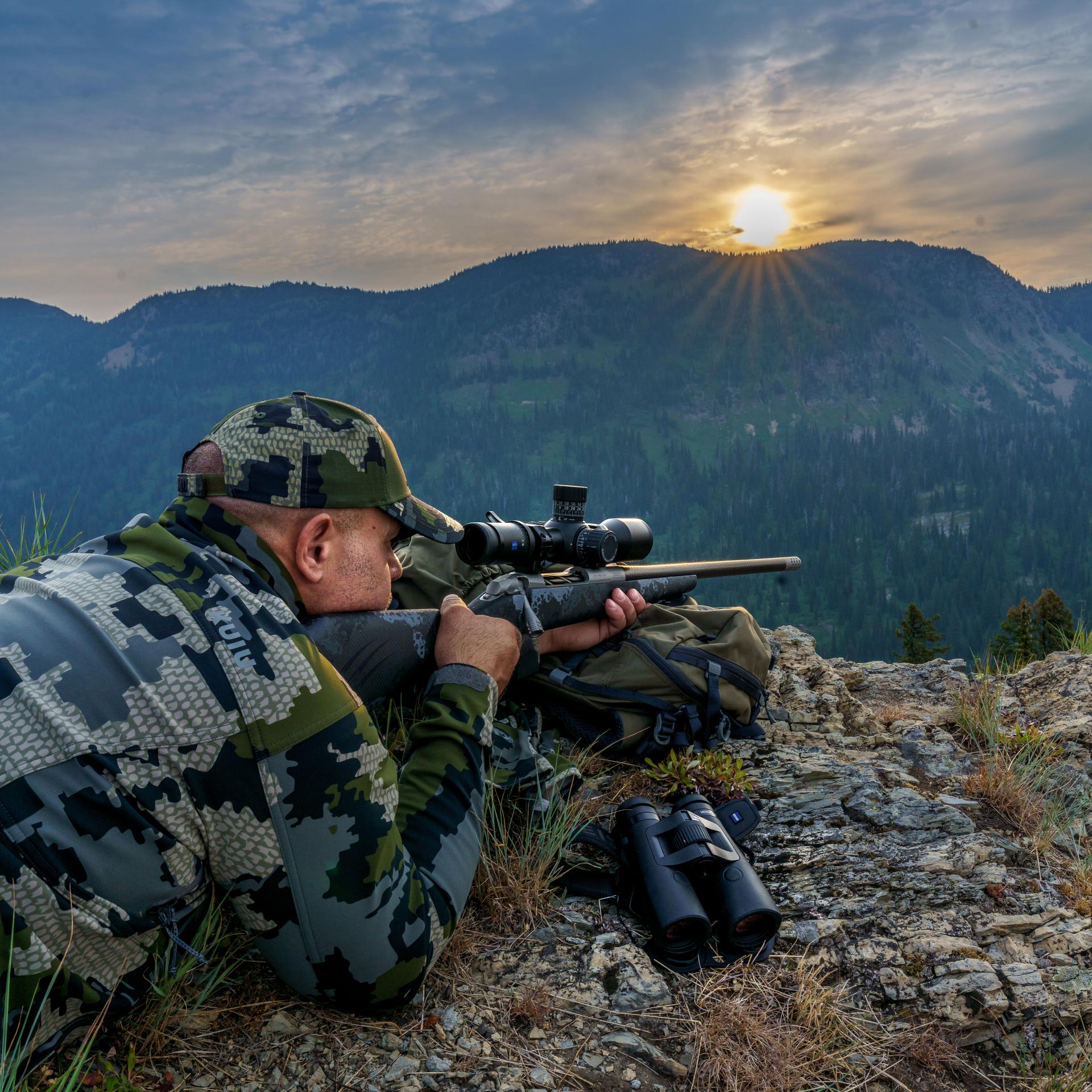 Hunter aiming with a ZEISS LRP S5 318-50 riflescope on a mountain ridge at sunset, illustrating long-range precision use