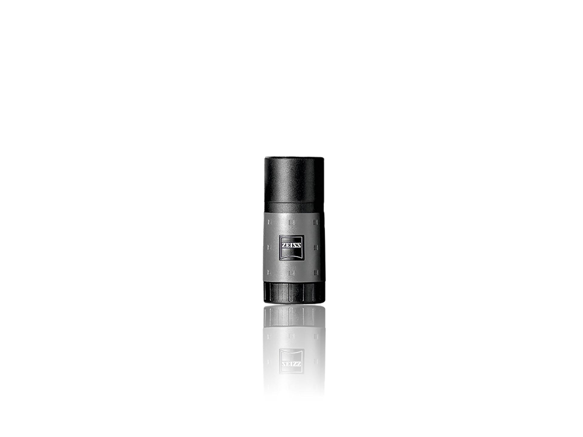 A compact, cylindrical ZEISS optical device with a black top and metallic body, featuring the ZEISS logo on the front, shown against a white background with a subtle reflection.