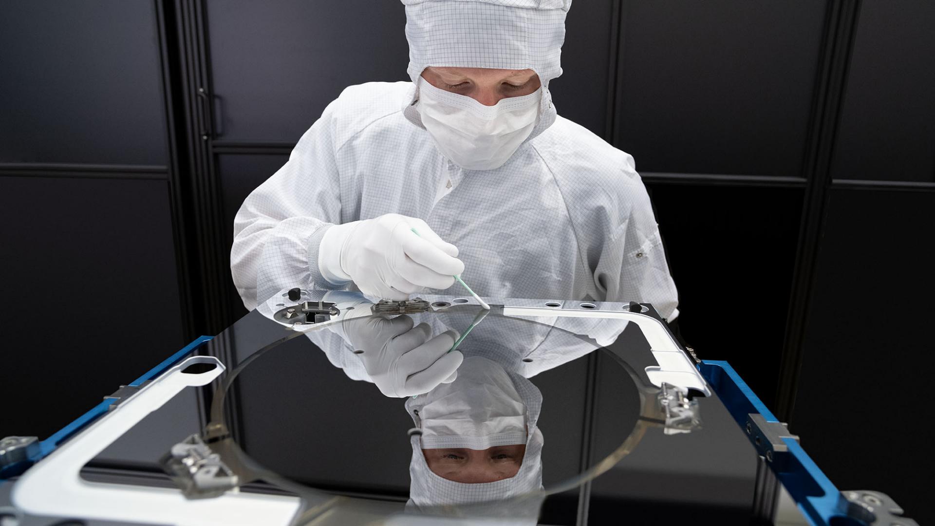 Ein Mitarbeiter der ZEISS SMT reinigt einen EUV Mirrorblock im Reinraumanzug