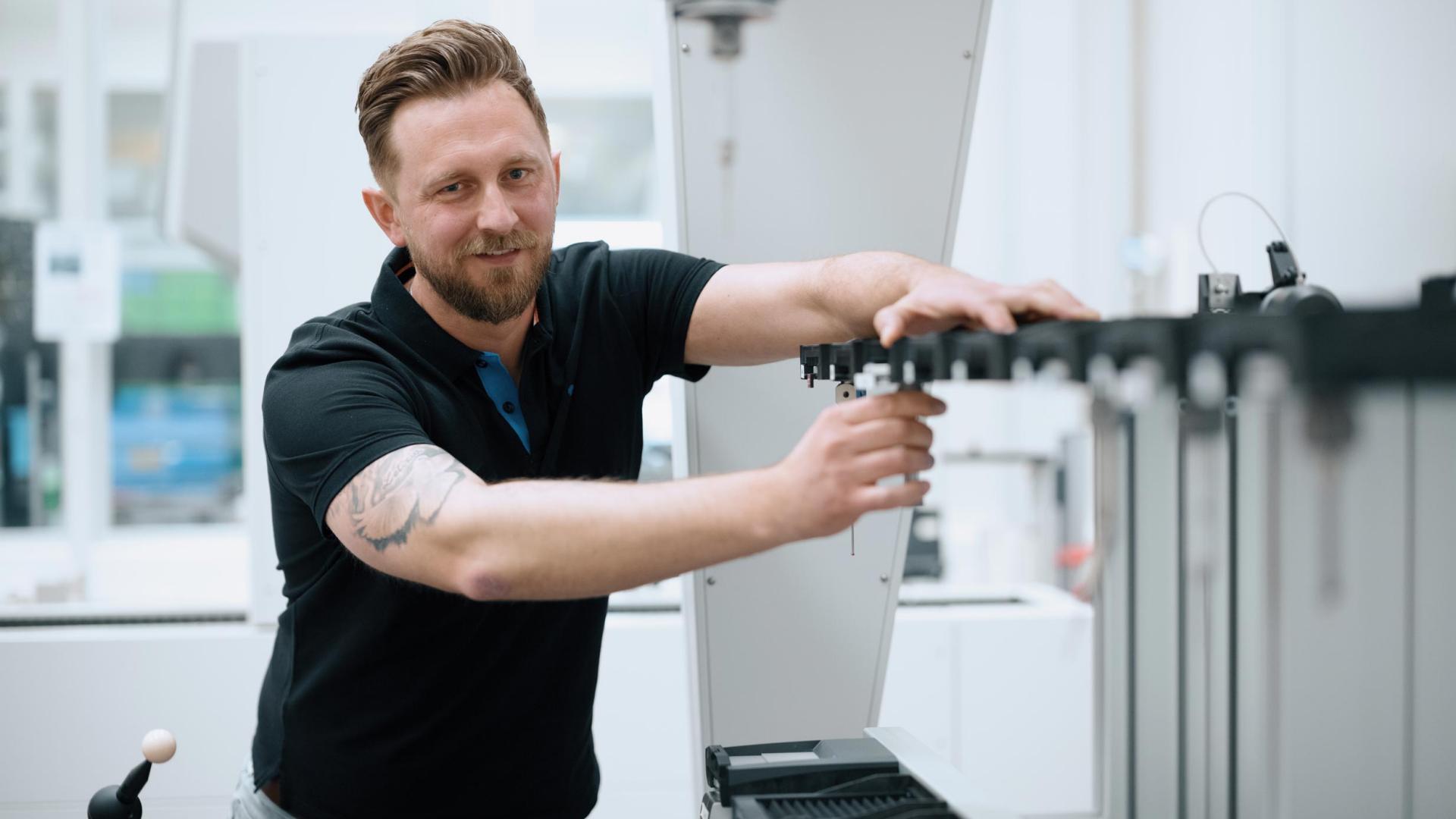 Artur arbeitet an einer Maschine bei seiner Arbeit bei ZEISS SMT