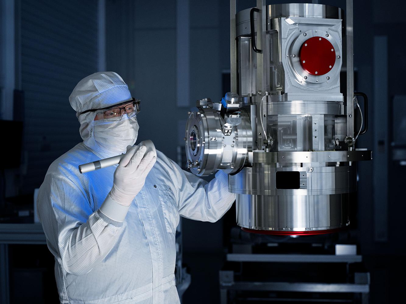 Ein Mitarbeitender der ZEISS SMT arbeitet im dunklen Reinraum an einer Waferinspektion.