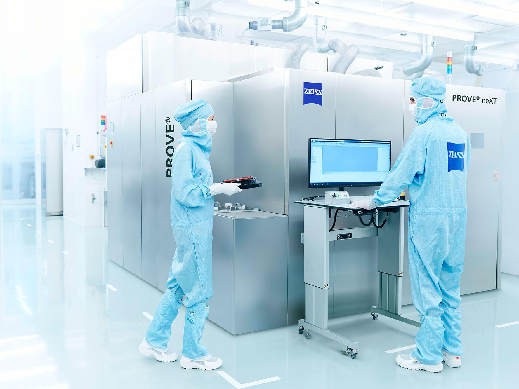 Zwei Mitarbeitende der ZEISS SMT arbeiten im Reinraum an einer Anlage. 