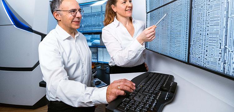 Zwei PCS-MultiSEM Mitarbeiter schauen sich die neueste Technologie auf einem Bildschirm an