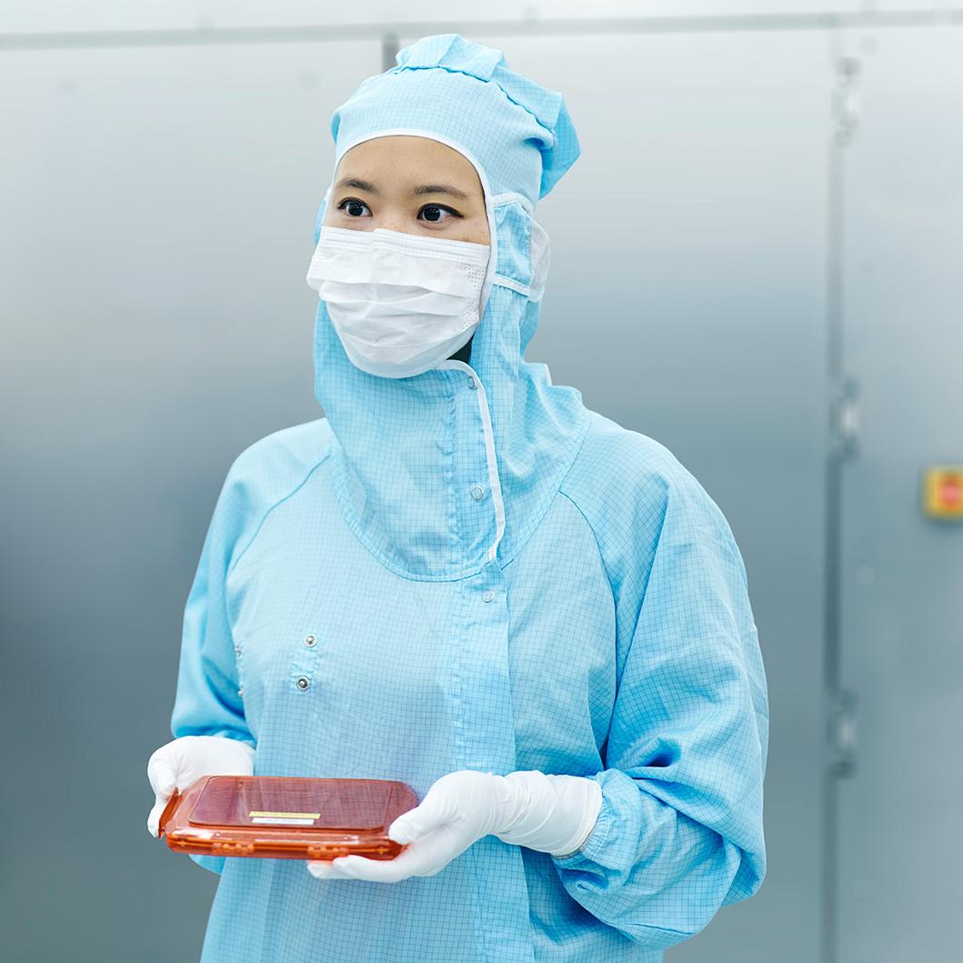 Eine  ZEISS Mitarbeiterin im Reinraum der SMT mit einer Photomaske.