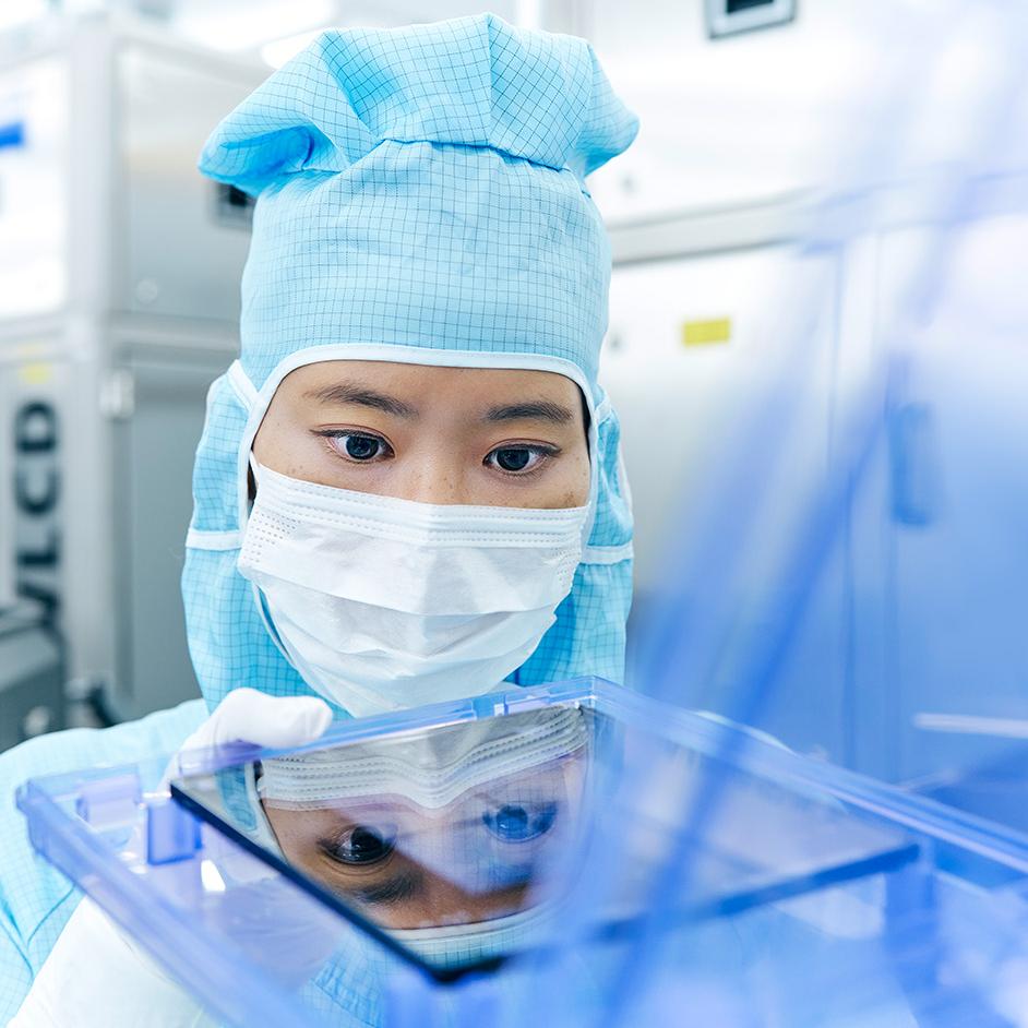 Eine Mitarbeiterin der ZEISS SMT arbeitet im Reinraum an einer Photomaske