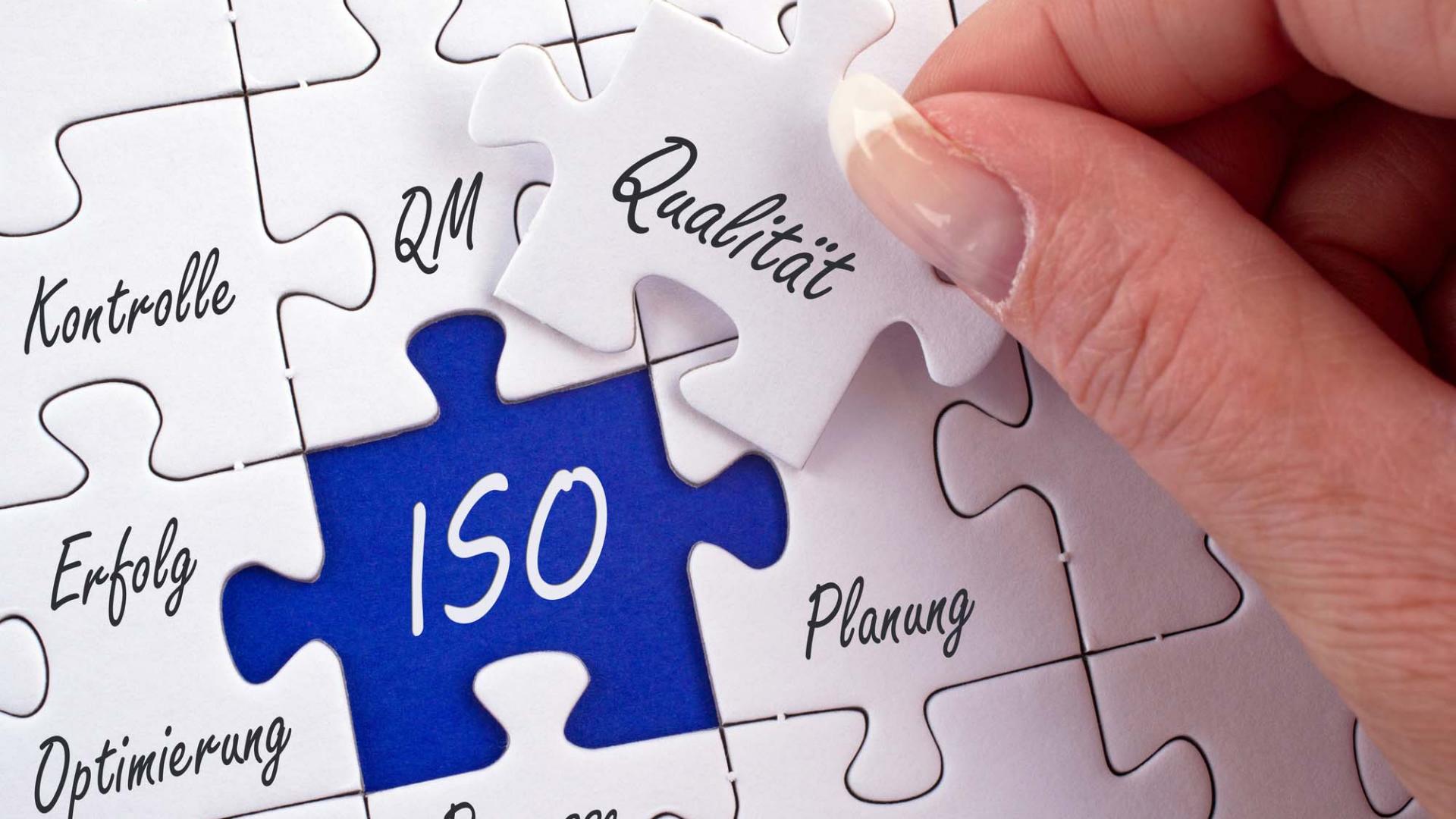 Eine Frau fertigt ein Puzzle mit Aufschriften wie Qualität, Planung, Prozesse oder ISO