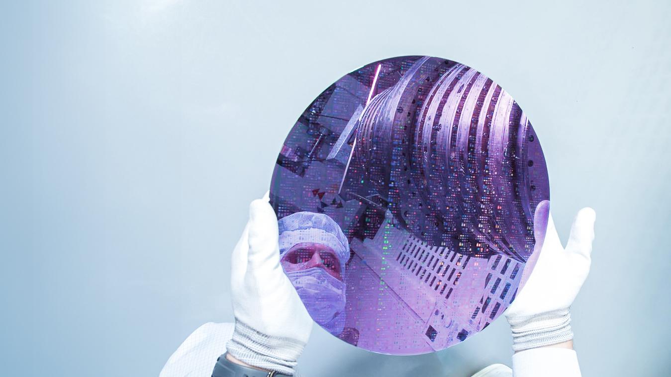 Ein ZEISS SMT Mitarbeiter hält, die für die DUV-Technologie wichtige Komponente in Form einer dünnen scheibenförmigen Siliziumscheibe – den sogenannten Wafer – in der Hand.