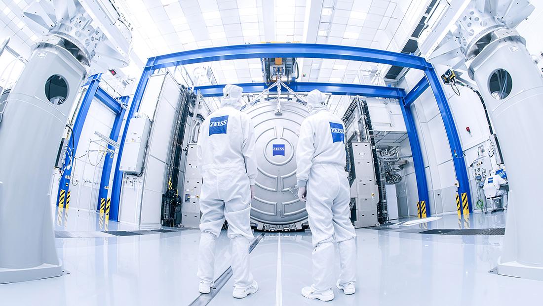 Zwei Mitarbeiter stehen vor der gigantischen Messtechnik für die Spiegel der High-NA-EUV-Technologie