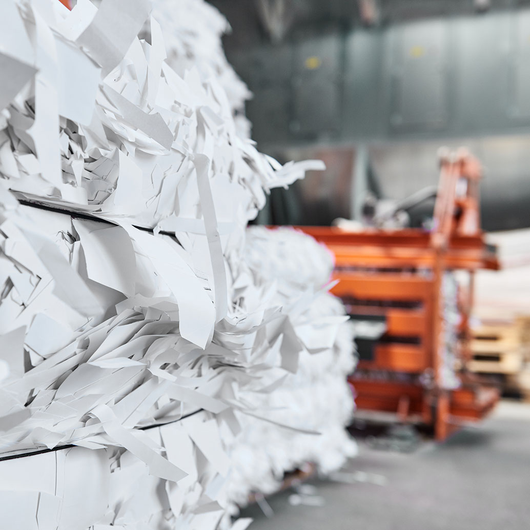 Eine Zerkleinerungsmaschine in einer Papierrecyclingfabrik zerkleinert Altpapier in quadratische Ballen, die wiederverwendet werden können. Das Recyceln von Abfallstoffe verringert die Umweltverschmutzung und schützt den Planeten.