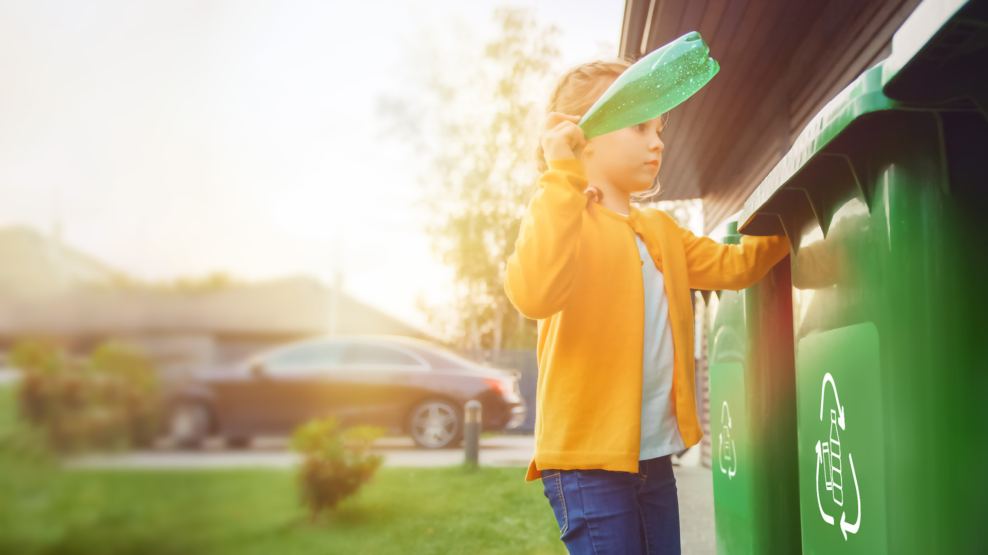 Junges Mädchen wirft eine leere Plastikflasche in einen Mülleimer. Sie benutzt den richtigen Mülleimer. Recycling