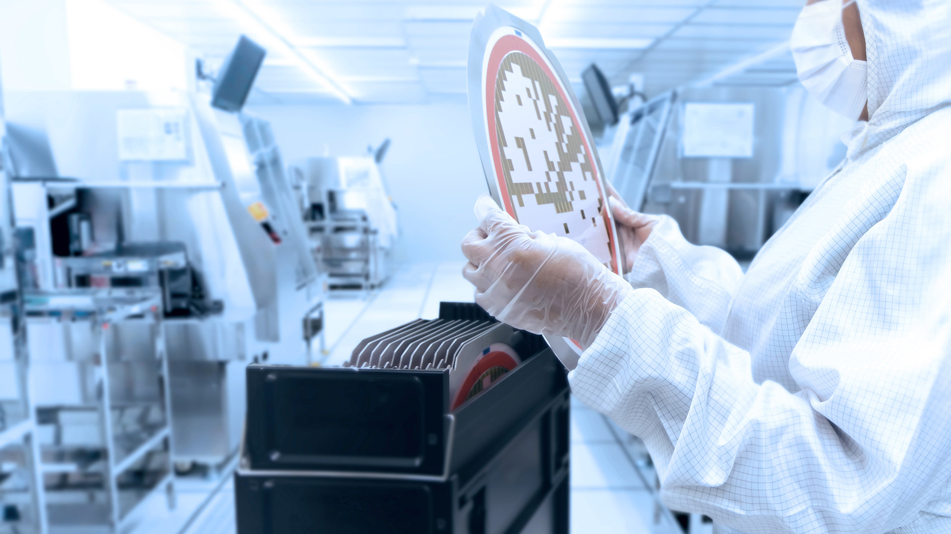 Angestellter in einem sterilen Raum hält Wafer in seiner Hand