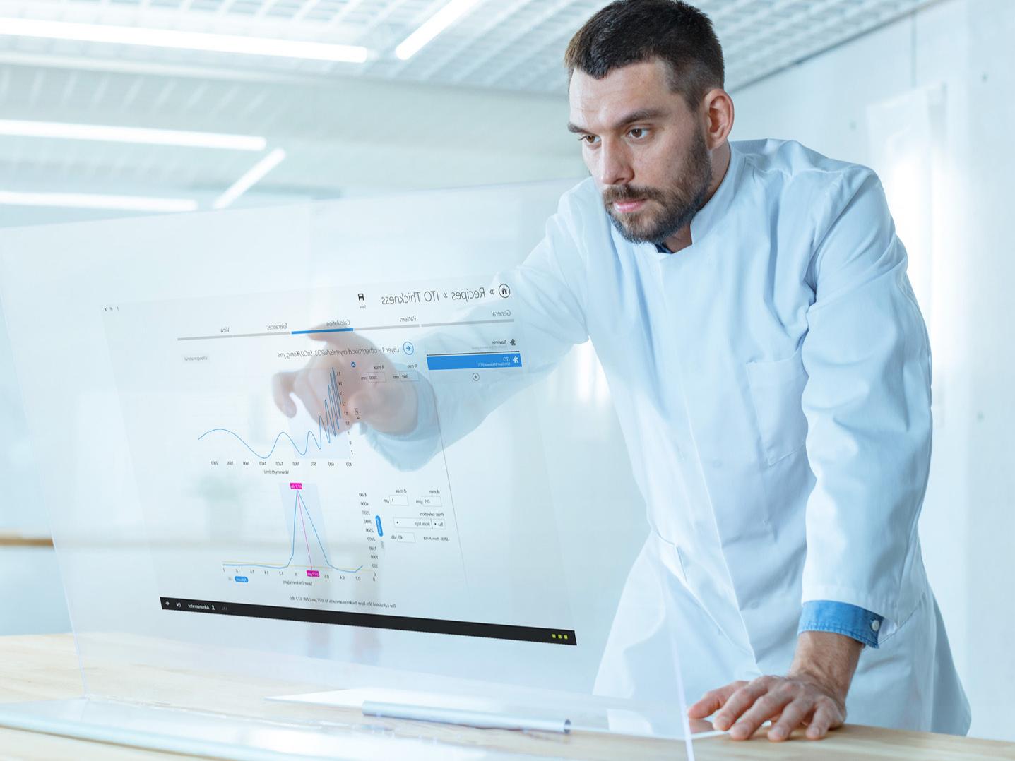 Futuristisches Labor. Männlicher Wissenschaftler arbeitet an seinem transparenten Computerbildschirm, ThinProcess Software auf dem Bildschirm, Batch-Verarbeitungsanwendungen