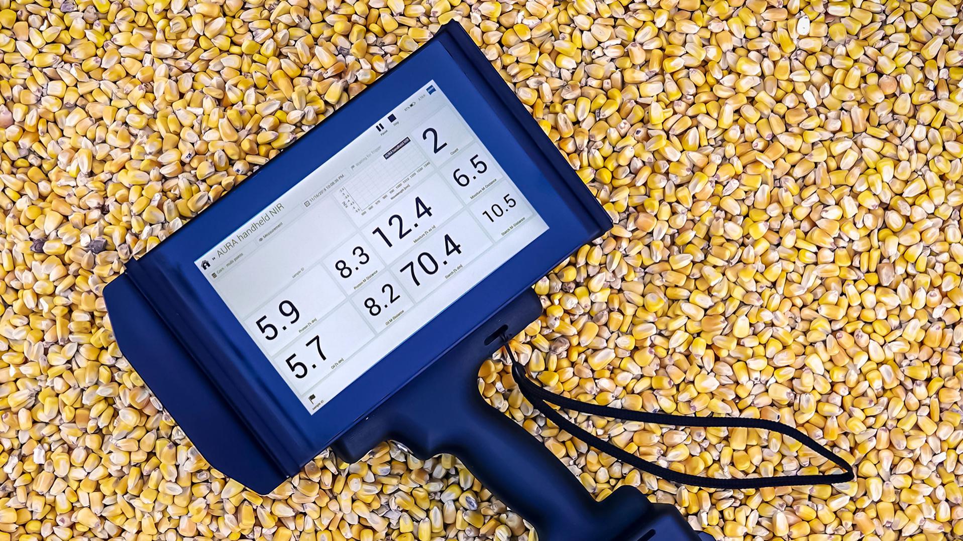 AURA® handheld NIR with InProcess Software showing on display, lying on corn